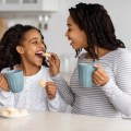 Happy black mom feeding her kid with&nbsp;cookies